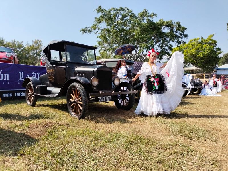 Ford T de época junto a una mujer con traje típico mexicano